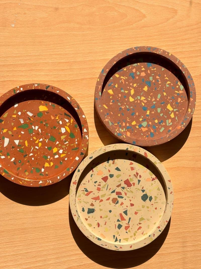 Three round eco-resin catch-all trays with a colourful terrazzo chip effect