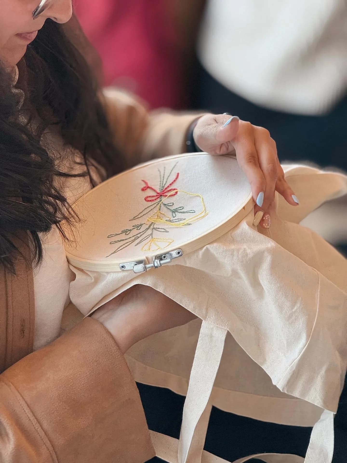Telaio da ricamo con un motivo floreale su una borsa di cotone grezzo, in un laboratorio di Creo Workshop