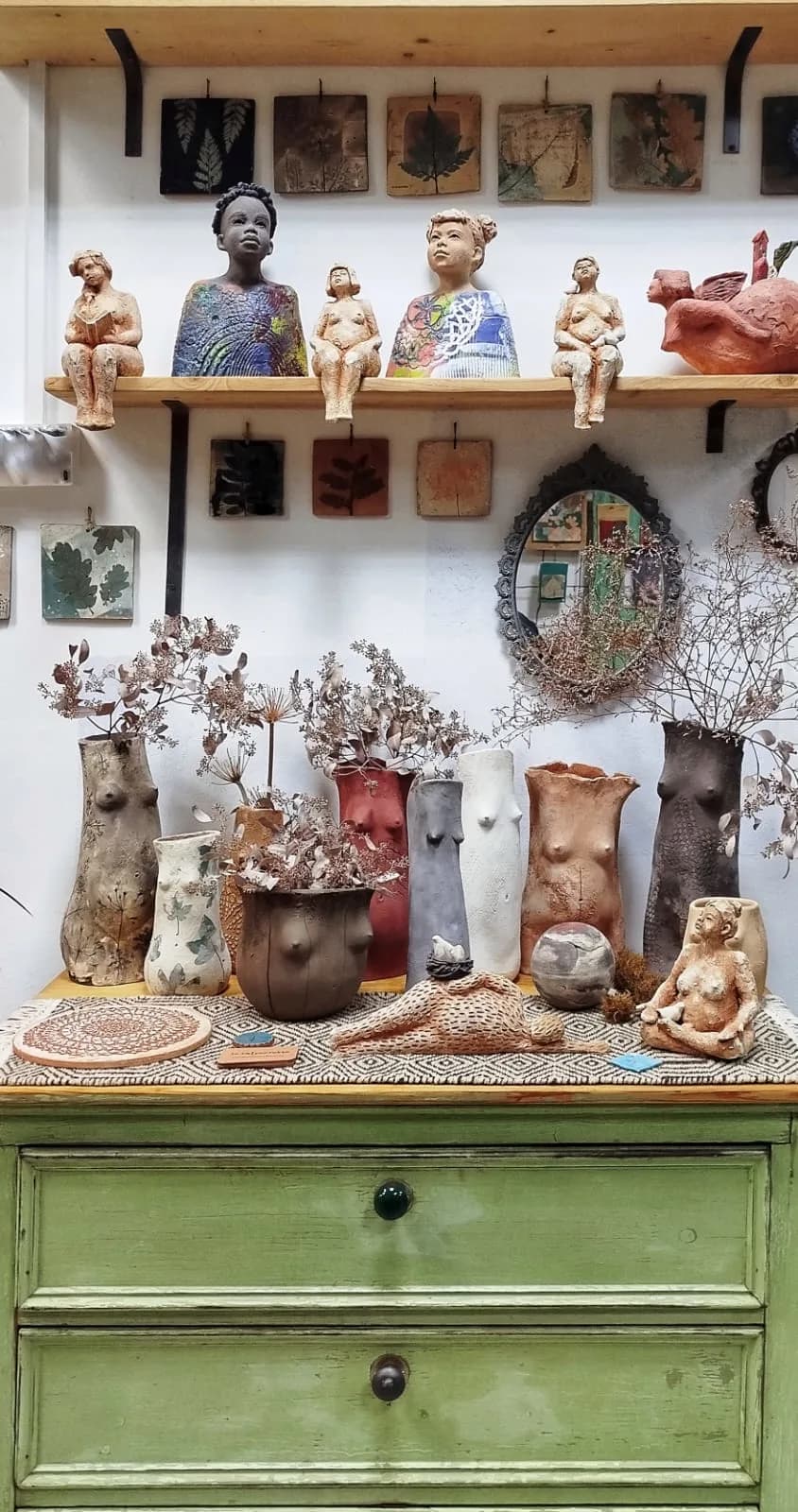 Shelf in the Le Imperfette Ceramica studio with hand-built figures, vessels and clay tiles