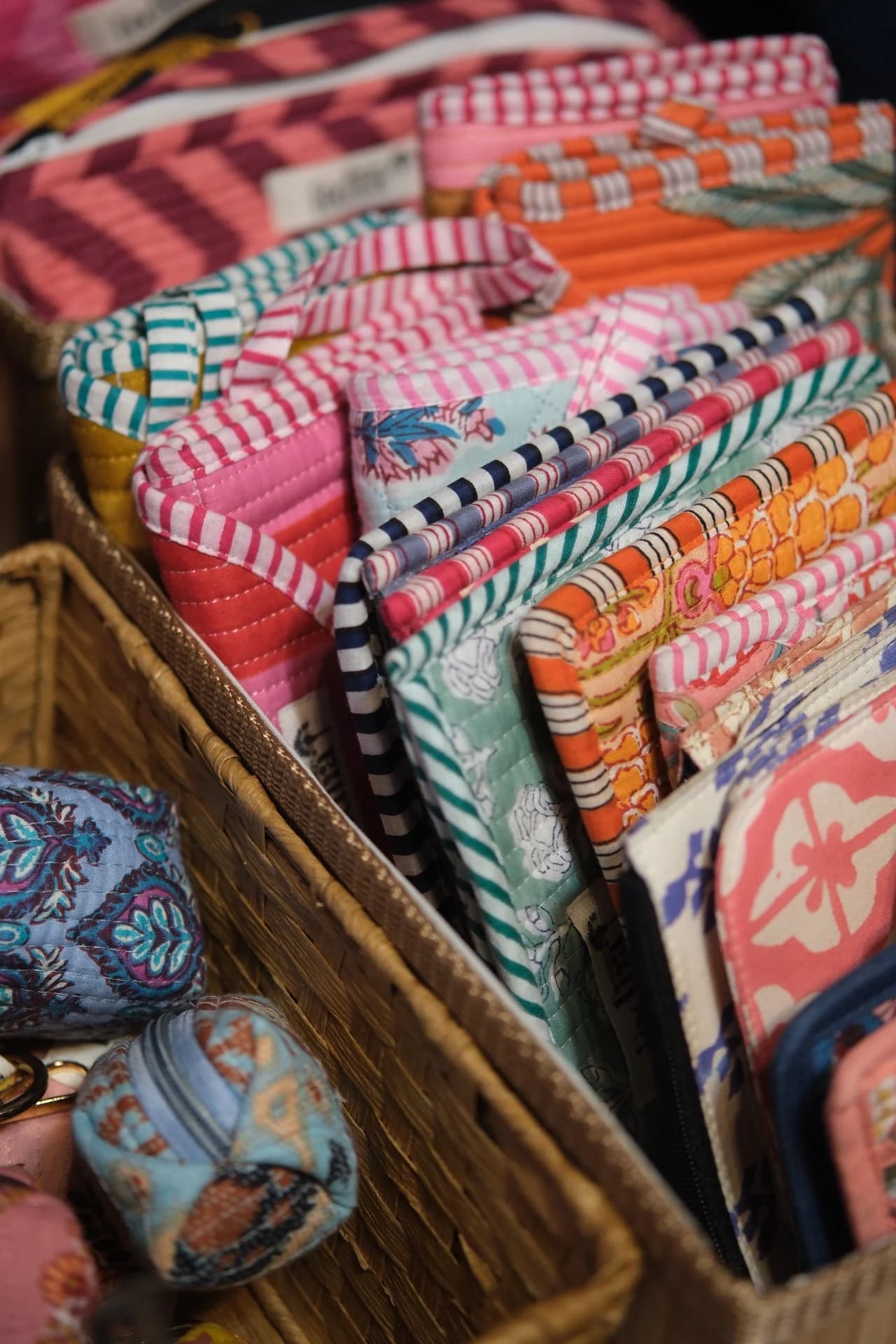 Patterned fabric pouches and cases gathered in a basket on a stall at Comunella Market